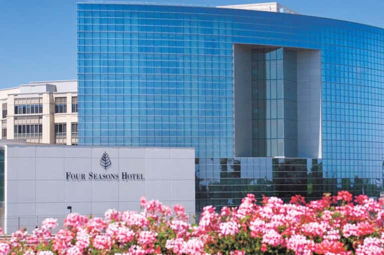 Four Seasons Hotel modern blue glass building with pink flowers and clear sky