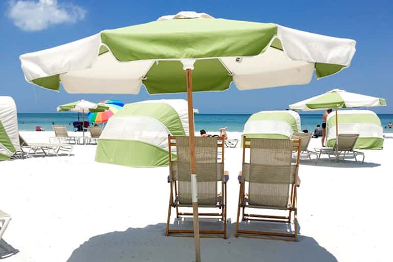 Beach umbrellas and lounge chairs with ocean view under bright blue sky