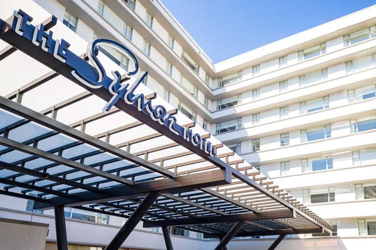 Modern hotel entrance with blue neon sign and contemporary architecture under clear sky