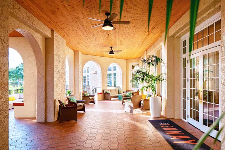 Covered arched loggia with comfortable seating, wooden ceiling, and resort views