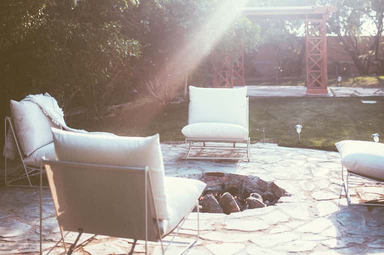 Vintage sepia-toned outdoor seating area with cream armchairs surrounding a fire pit