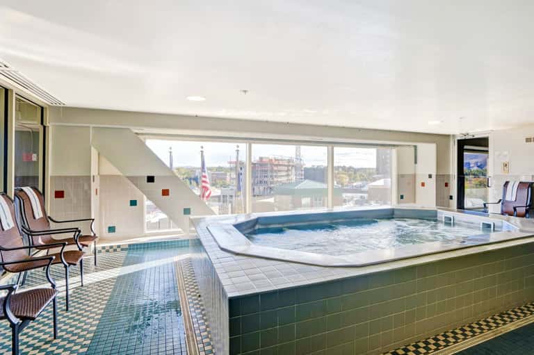 Indoor spa with hot tub and large windows overlooking cityscape with American flag