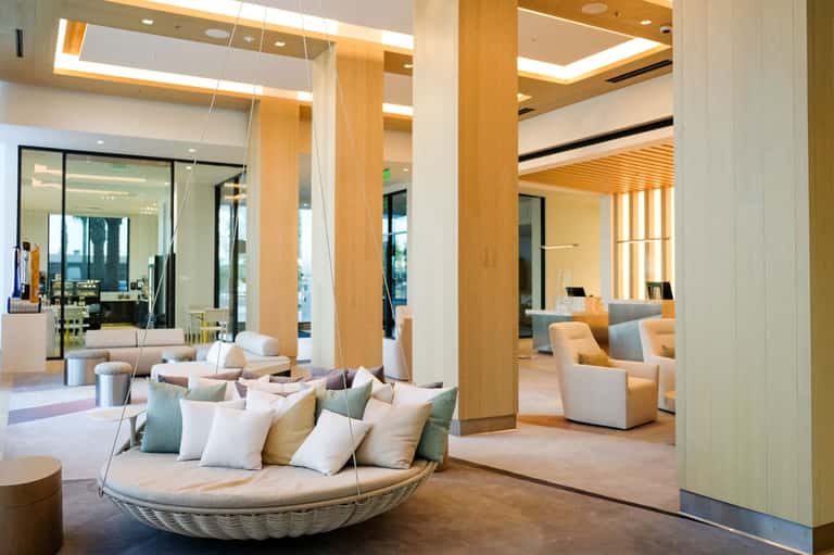 Modern spa lobby with suspended woven chair, wood columns, and mirrors reflecting serene interior