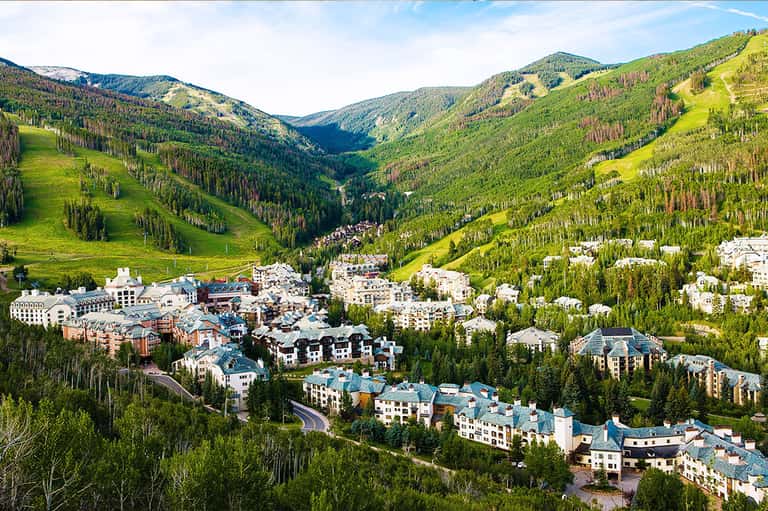 Aerial view of mountain resort nestled in forested valley with multiple buildings