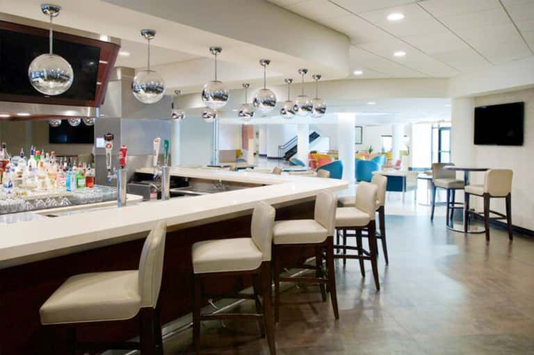 Modern hotel bar with spherical pendant lights, cream bar seating, and contemporary lounge area
