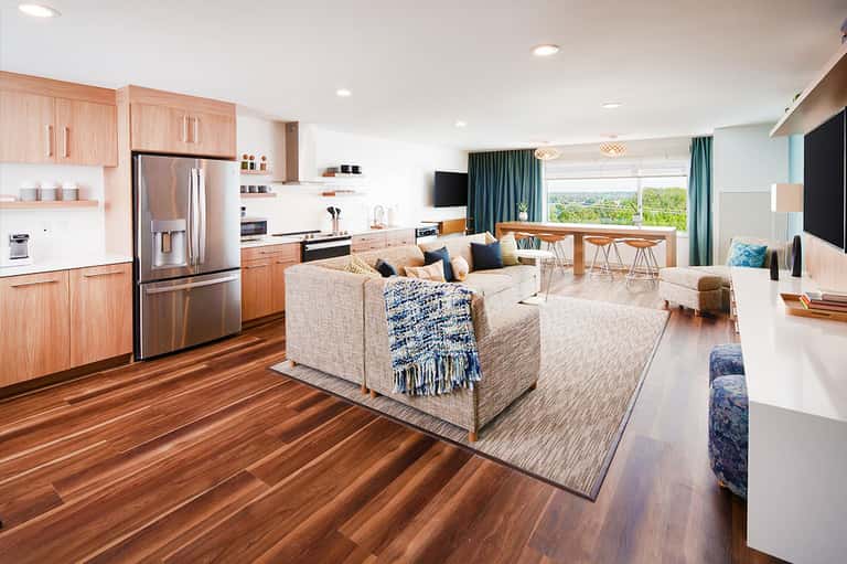 Modern open-concept suite with light wood cabinetry, stainless steel appliances, and ocean view windows