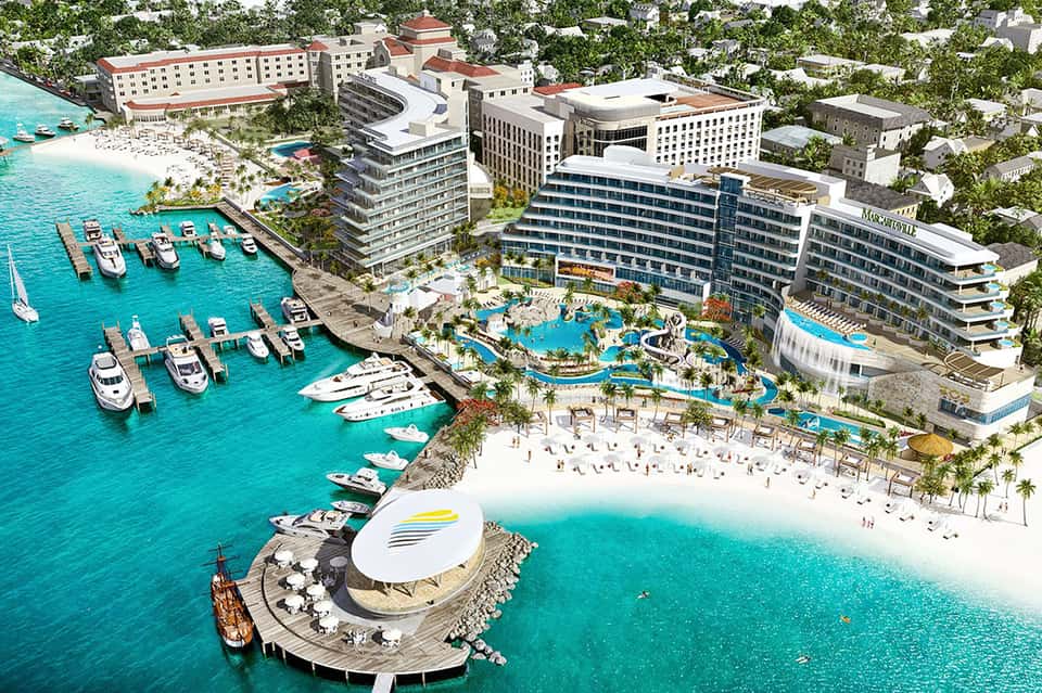 Aerial view of luxury beachfront resort with pools, marina, and turquoise waters