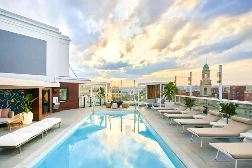 Modern rooftop pool with city skyline views, lounge chairs, and historic church dome in background