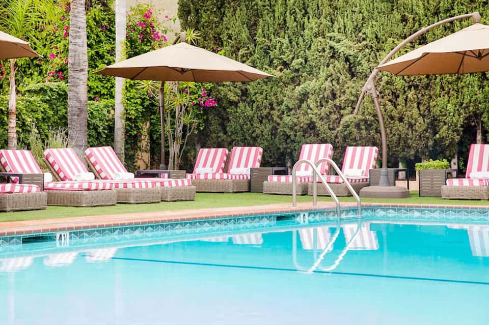 Resort pool with pink and white striped loungers, umbrellas, and manicured grounds