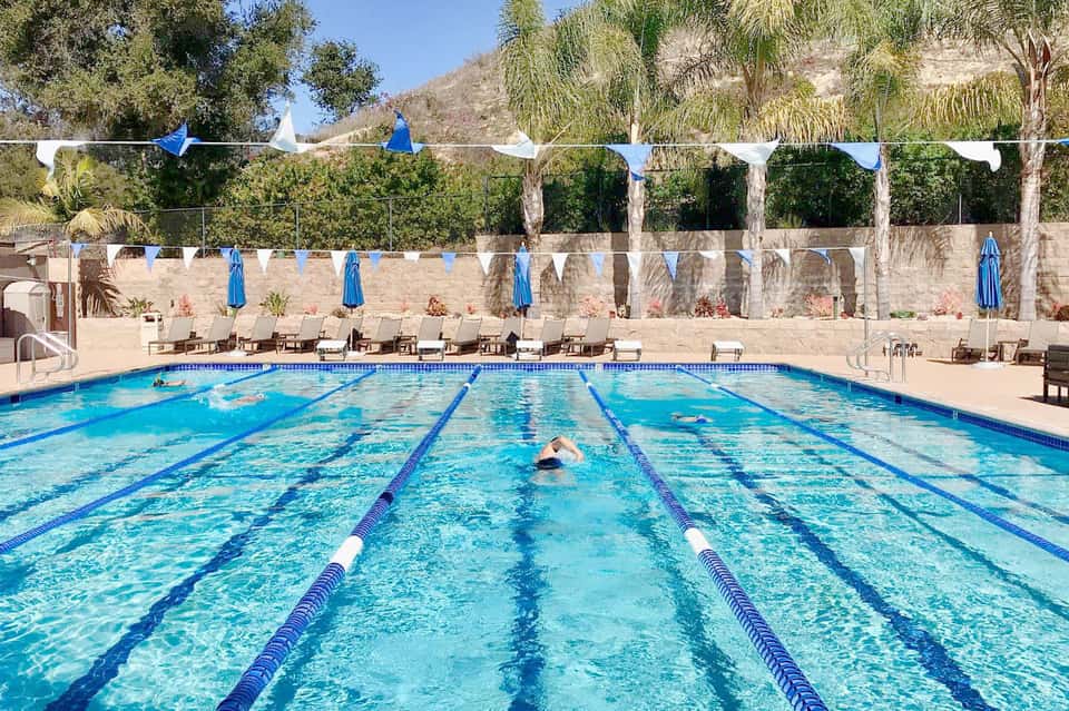 Olympic-length lap pool with lane dividers and mountain backdrop during daytime