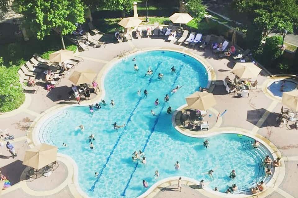 Aerial view of kidney-shaped swimming pool with sunbathers and umbrellas