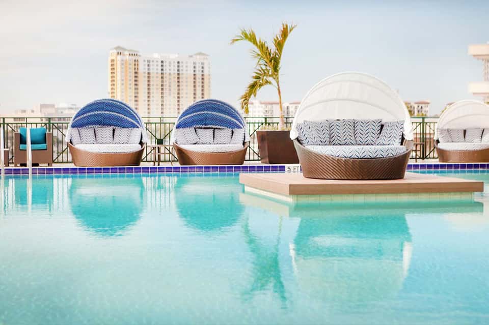 Resort pool with decorative lounge chairs featuring white canopies and blue and white patterns