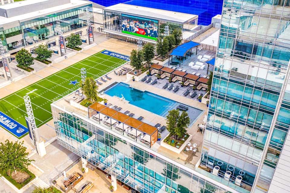 Aerial view of luxury resort with pool, fitness field, and modern high-rise buildings