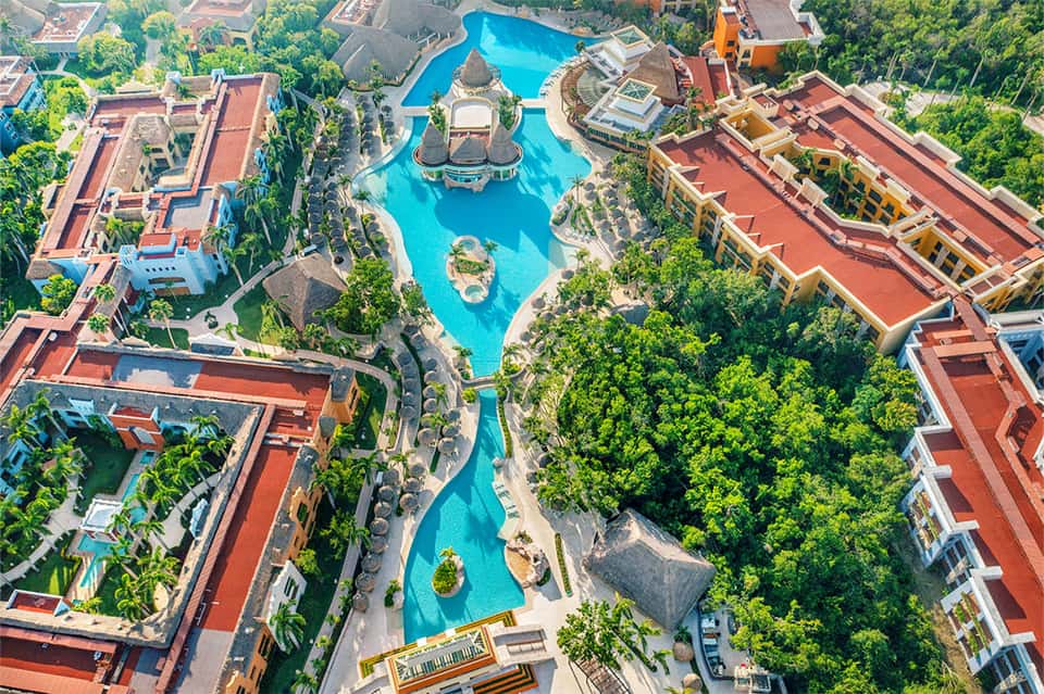 Aerial view of sprawling resort with large turquoise pool and tropical landscaping