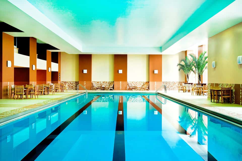 Indoor lap pool with bright turquoise water, colorful walls, and wooden furnishings