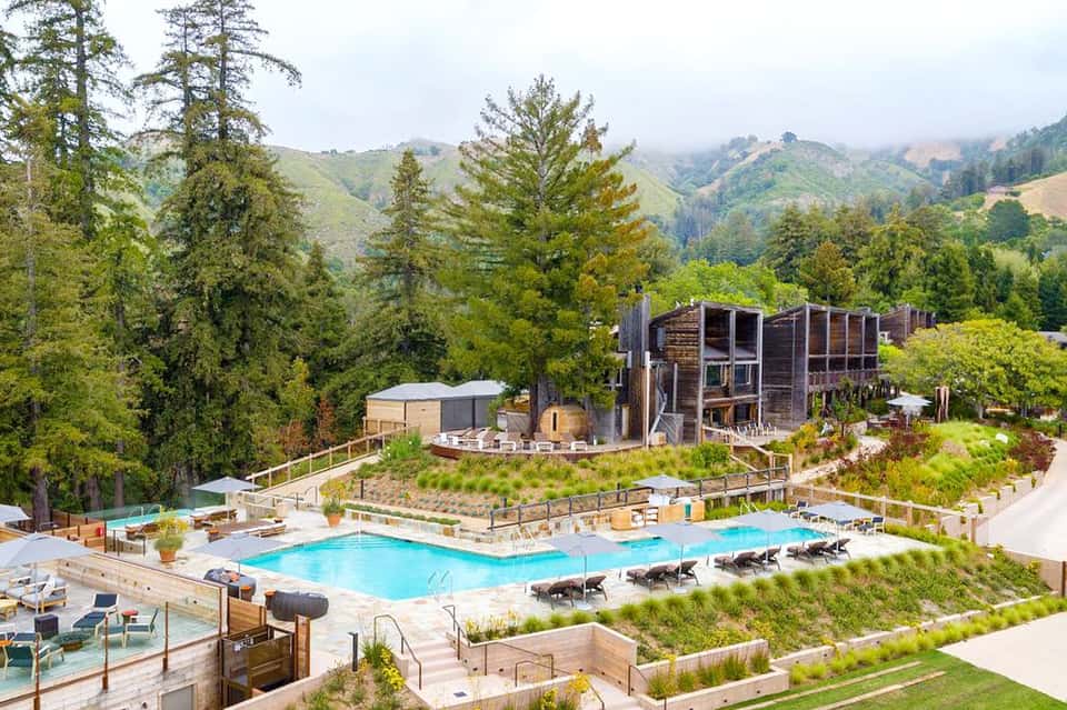 Modern resort pool nestled in forested mountains with lounge chairs and facilities