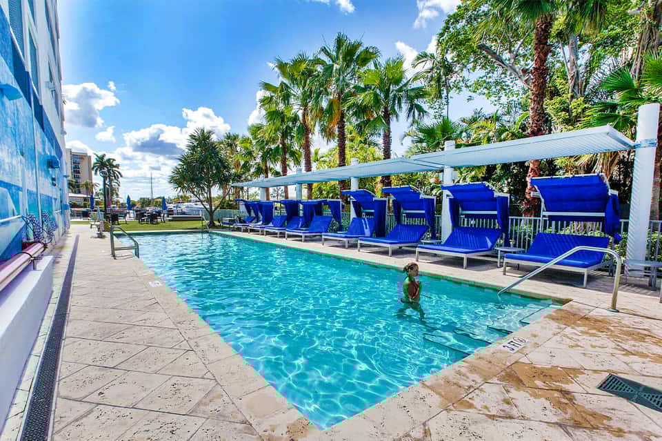 Resort pool with blue lounge chairs and white pergola shade structures