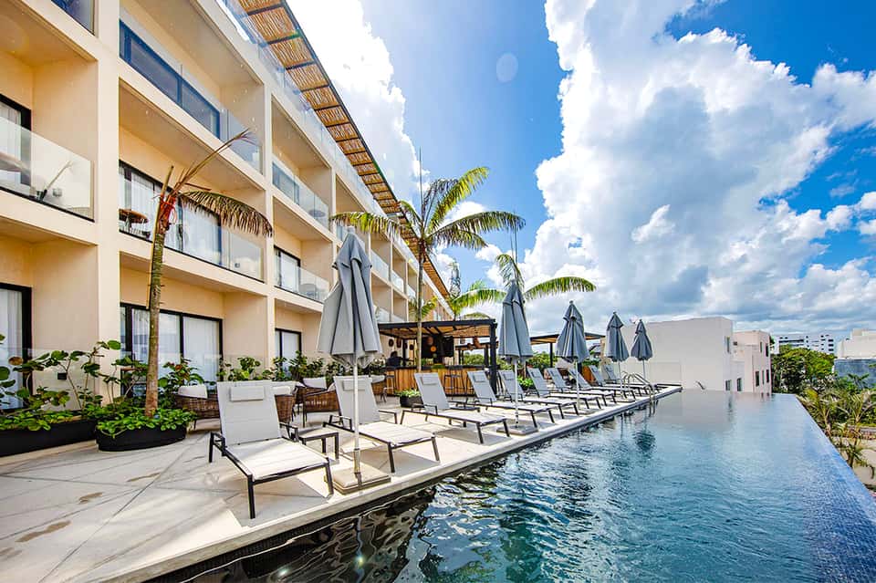 Resort pool with umbrellas, lounge chairs, and tropical landscaping