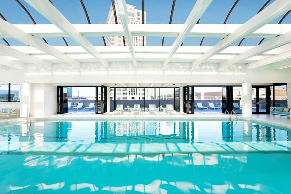 Indoor lap pool with glass ceiling, white structural beams, and modern architectural design