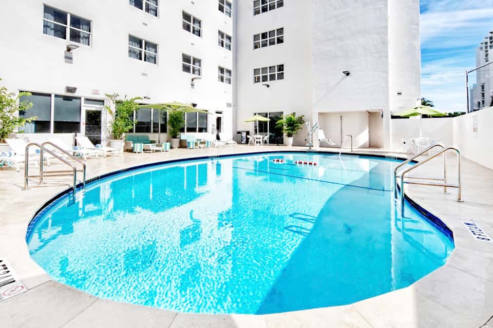 Resort indoor swimming pool surrounded by white walls and large windows in modern facility