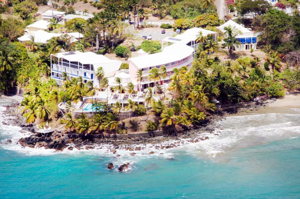 Beachfront resort property on tropical hillside with white curved buildings and turquoise water