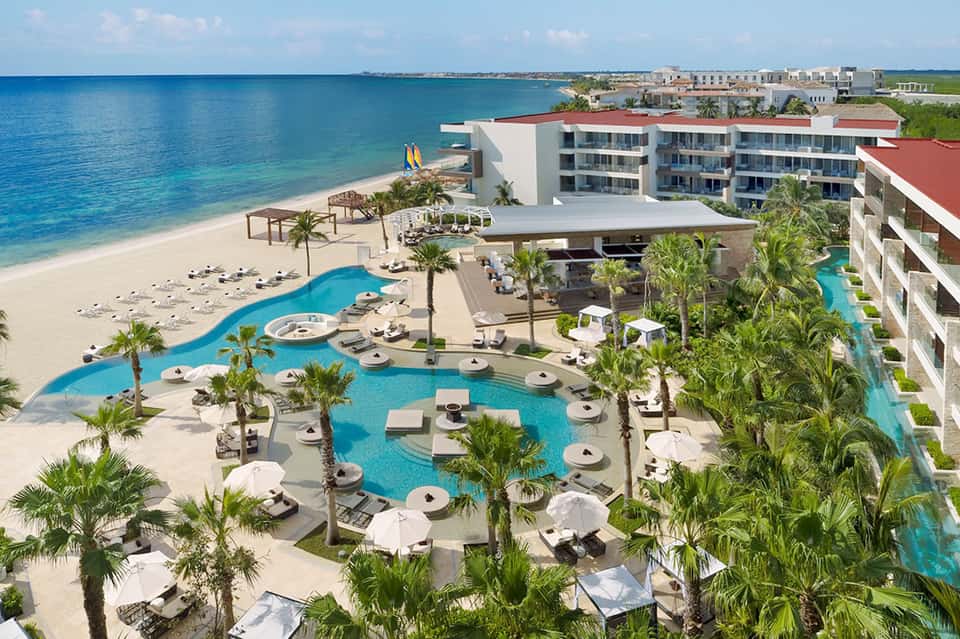 Beachfront all-inclusive resort with lagoon-style pool, palm trees, and pristine beach access