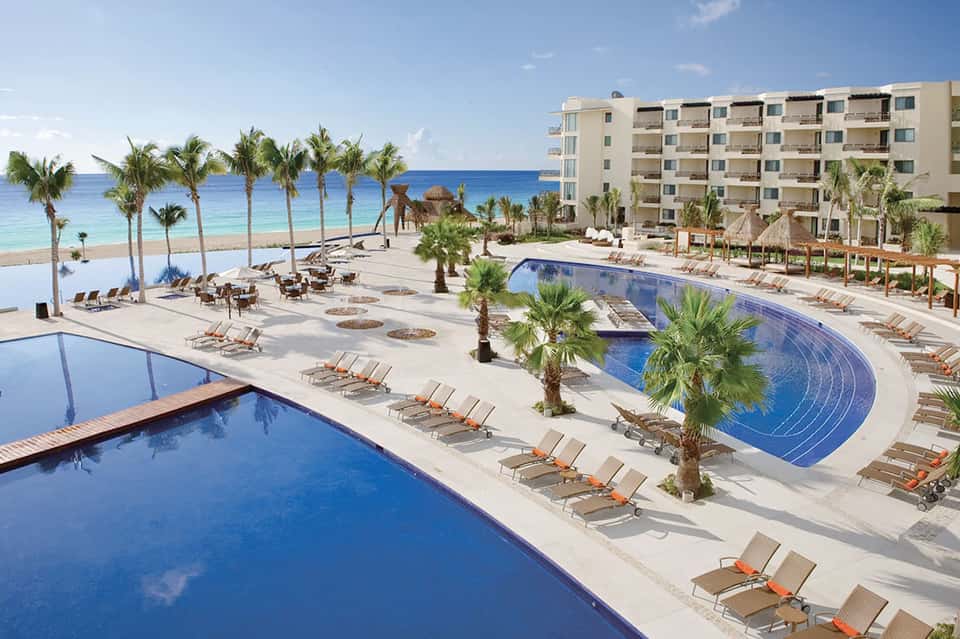 Beachfront resort with multiple pools, palm trees, lounge chairs, and ocean access with sand beach