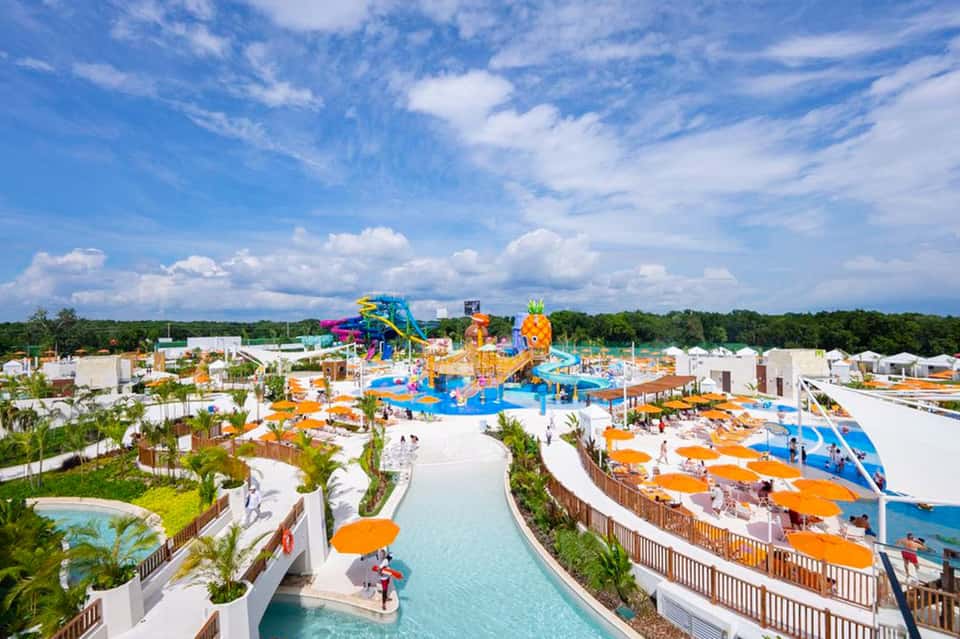 Aerial view of colorful water park with slides, pools, and orange umbrellas