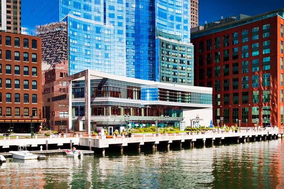 Waterfront hotel with modern white building, glass towers, red brick facades, and waterside plaza with seating
