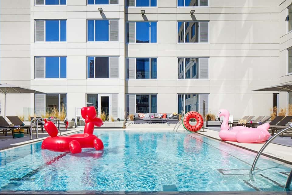 Resort swimming pool with red and pink inflatable pool floats in front of modern white building