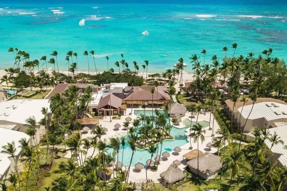 Beachfront aerial view of resort pools, tropical grounds, and pristine turquoise water