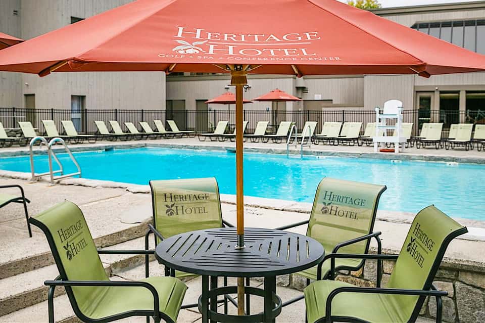 Heritage Hotel poolside seating area with red umbrella, lounge chairs, and blue swimming pool