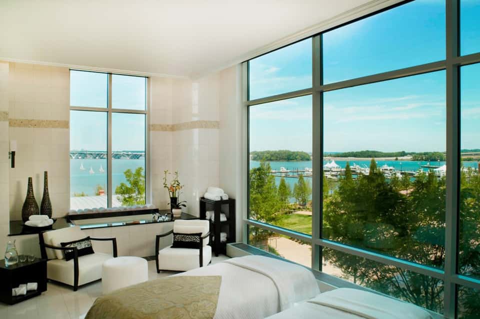 Luxury bedroom with floor-to-ceiling windows overlooking turquoise water and sailboats