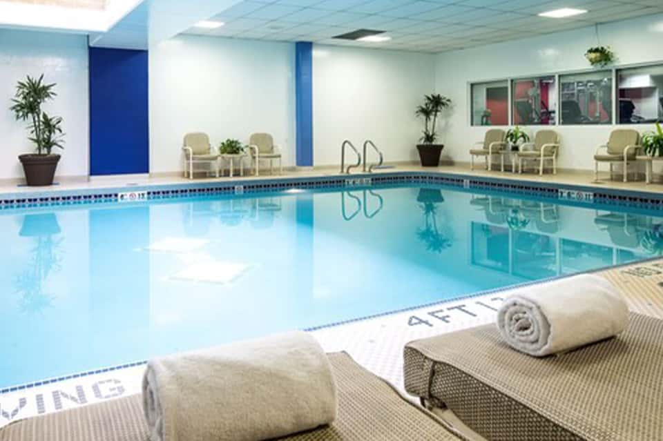 Indoor heated swimming pool with lap lanes, comfortable seating, and plants in bright facility