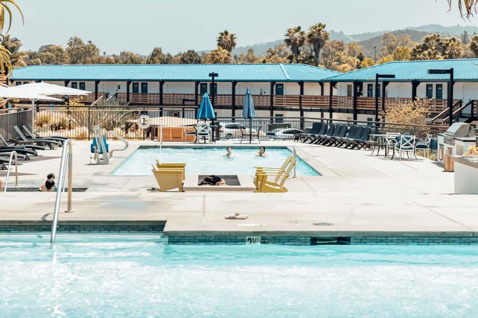 Bright blue pool with turquoise buildings and umbrellas under sunny skies