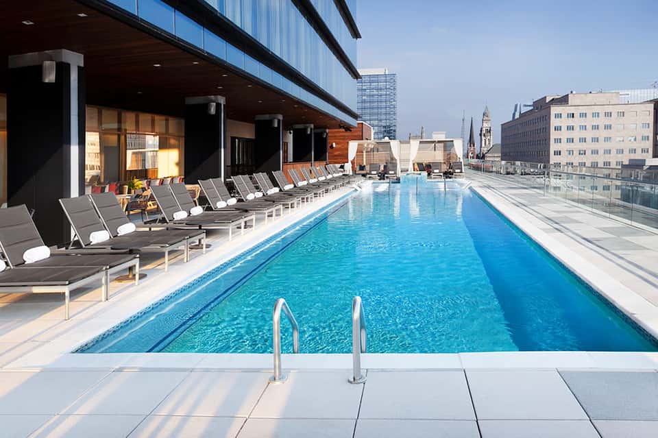 Modern rooftop pool with lap lanes, lounge chairs, and city skyline views