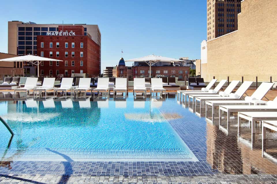 Rooftop pool with lounge chairs overlooking historic brick buildings and urban waterfront