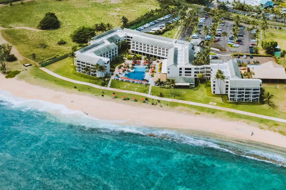 Aerial view of beachfront resort with pool, buildings, and white sand beach