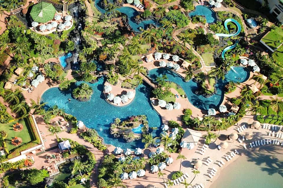 Expansive resort pool complex with multiple pools, water slides, loungers, and tropical landscaping