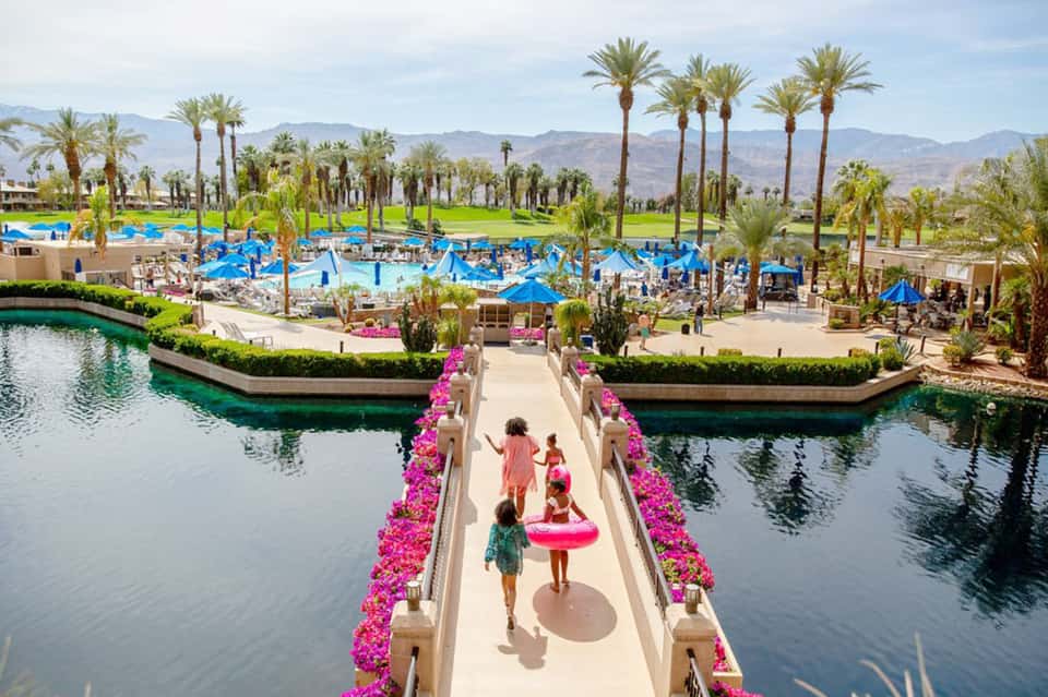 Resort entrance with pink flower-lined walkway over water canals and palm trees