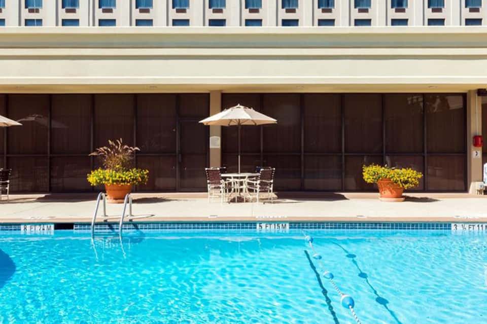 Resort outdoor pool with lap lanes, patio, umbrella, and modern hotel building