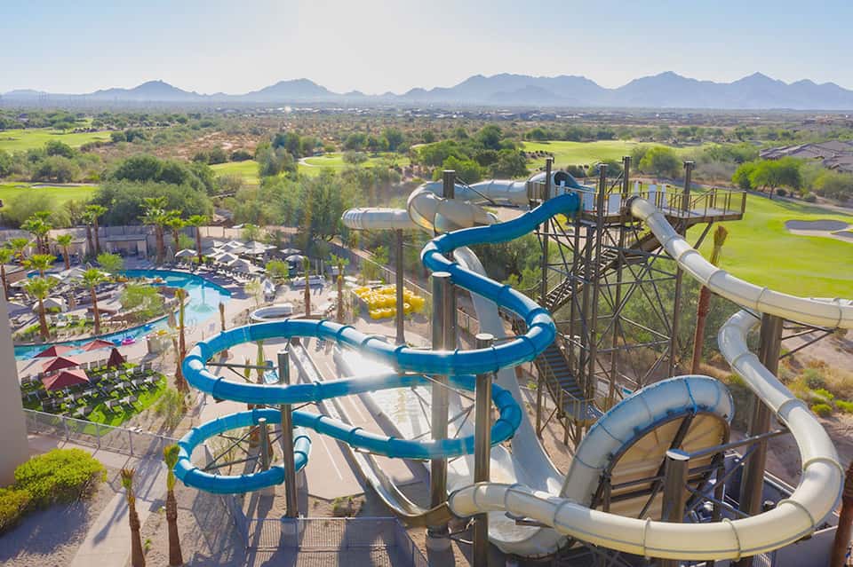 Aerial view of resort water park with blue slides and valley landscape