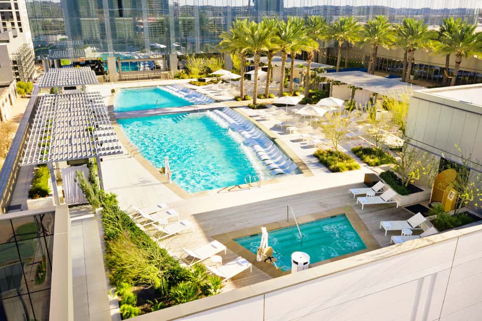 Aerial view of resort pools surrounded by palm trees and modern high-rise buildings