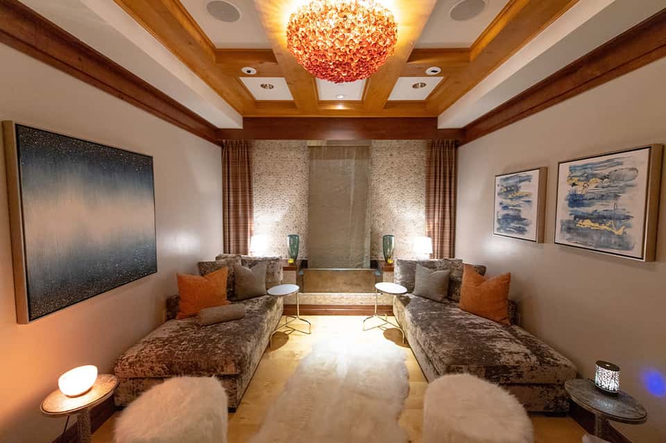 Elegant lounge room with decorative chandelier, dual seating areas, and artwork