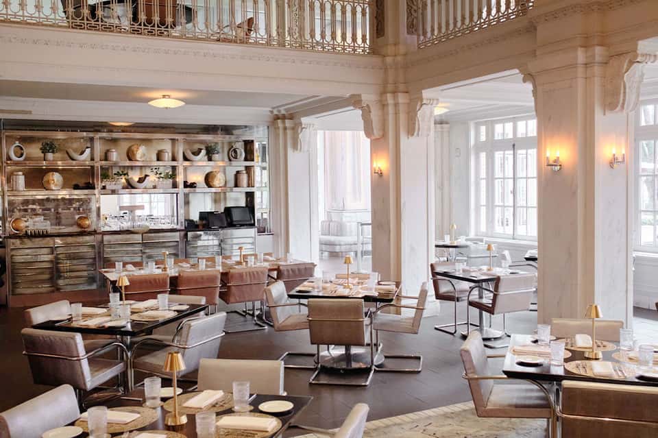 Elegant fine dining restaurant with tan leather chairs, decorative shelving, and ornate railings