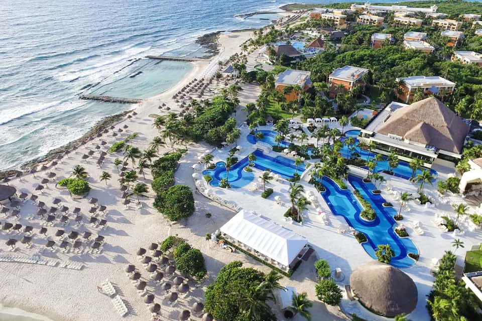 Aerial view of beachfront resort with pools, waterslides, beach, ocean, and palm trees