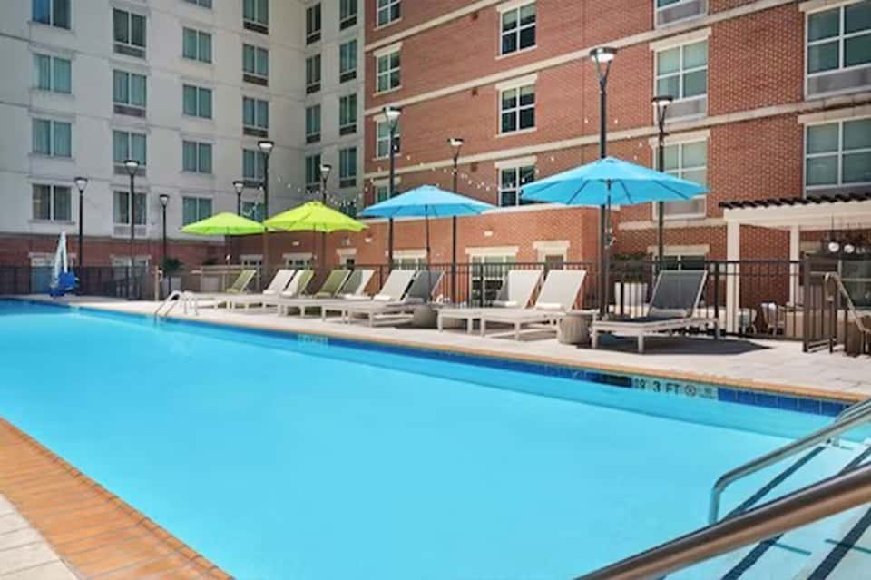 Hotel courtyard pool with blue water, colorful umbrellas, and lounge chairs