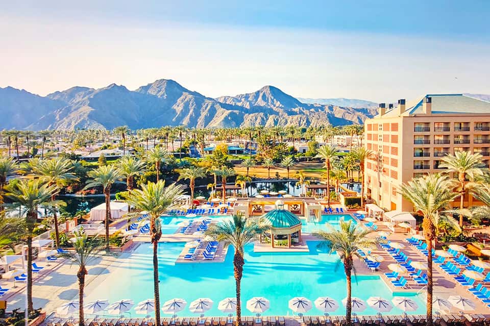 Resort pool complex with multiple pools, palm trees, and mountain backdrop in desert landscape