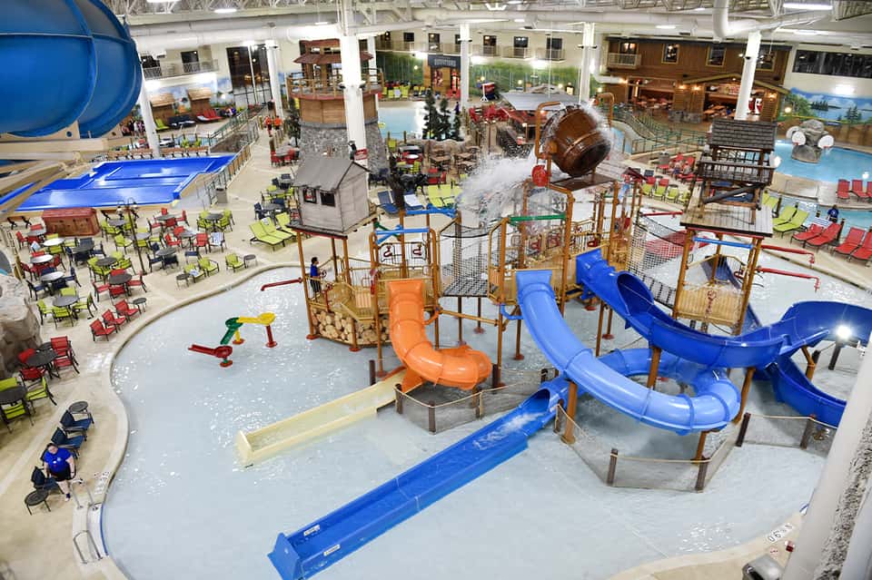 Indoor water park with large slides, play structures, pools, and spectator seating