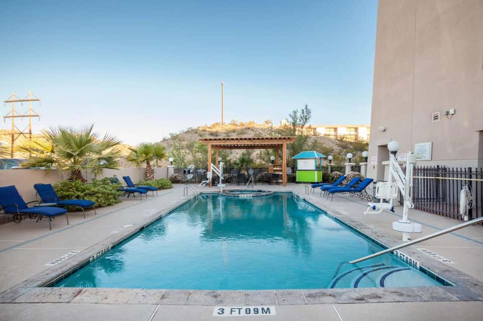 Desert resort pool with blue loungers and natural hilltop setting
